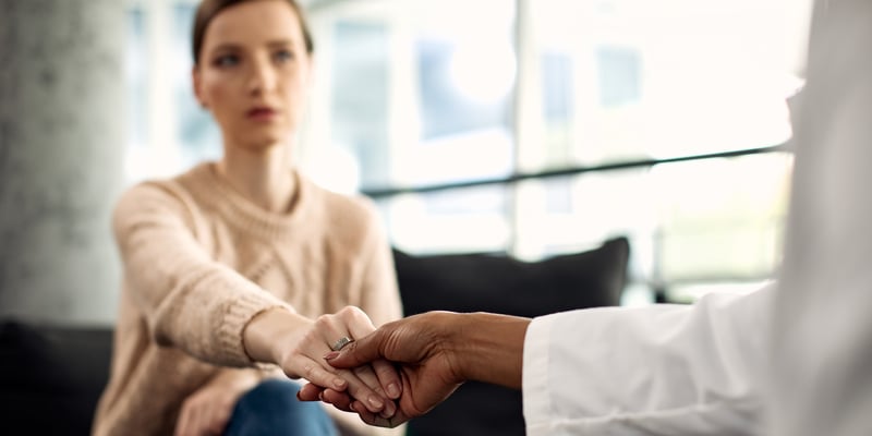 primer-plano-de-una-paciente-y-un-profesional-de-la-salud-mental-tomandose-de-la-mano-durante-la-psicoterapia-1